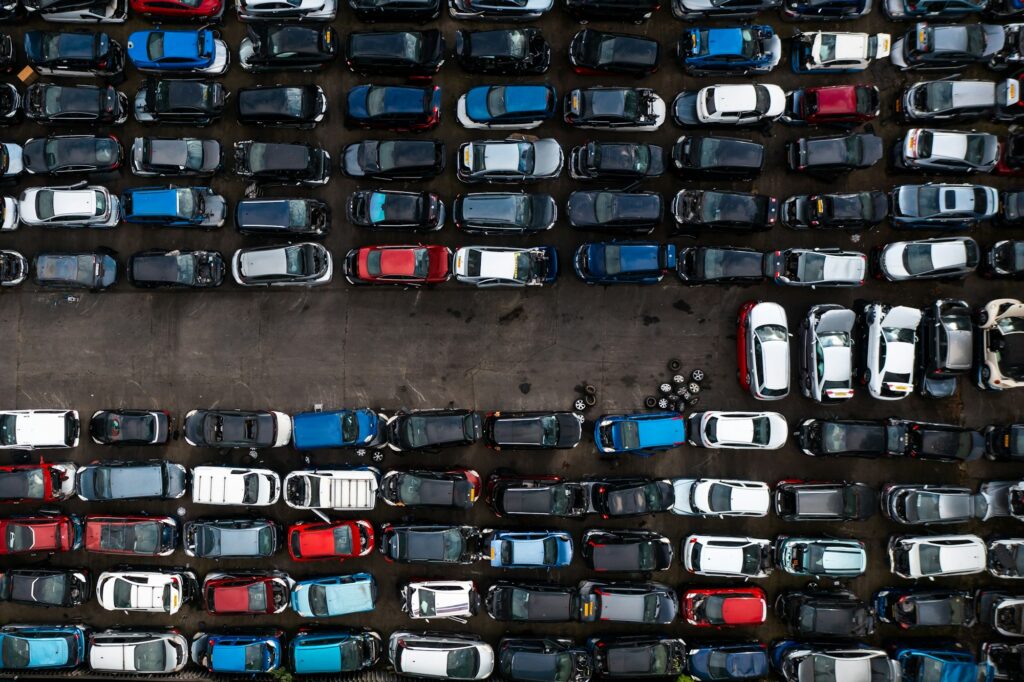 Aerial view directly above a scrap metal yard with rows of damaged cars